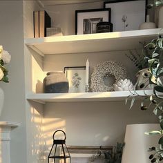 a white shelf filled with vases and other items next to a lamp on top of a table