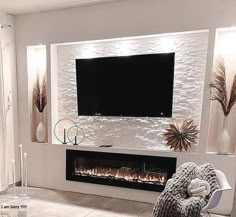 a living room with a large television mounted on the wall and a fire place in front of it