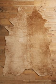 a brown and white animal skin rug sitting on top of a wooden floor next to a wall