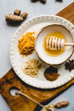 a bowl filled with honey and spices on top of a wooden cutting board next to other ingredients