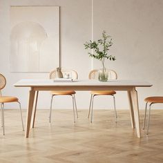 a dining table with four chairs and a vase on top of it in an empty room