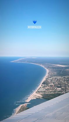 an airplane wing flying over the ocean and beach