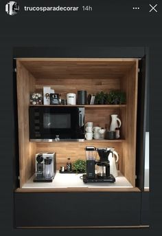 a coffee maker and some cups on a counter in front of a black microwave oven