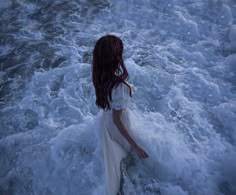 a woman is standing in the ocean waves