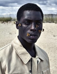 a man with black skin and gold nose piercings on his face in the desert