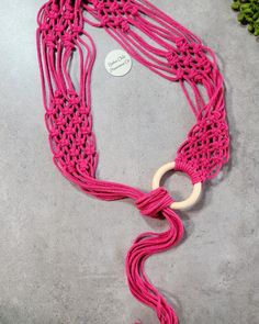 a pink crocheted necklace with a wooden ring