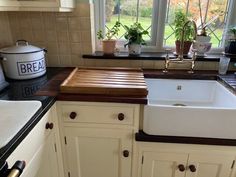 a kitchen with white cabinets and brown counter tops, an apron style sink and window