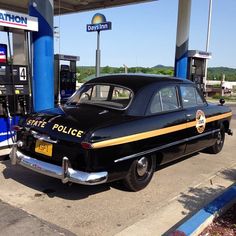 an old police car parked at a gas station