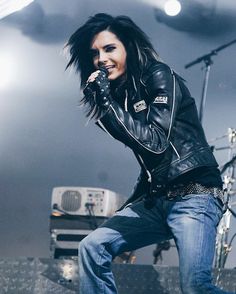 a woman in black jacket and jeans on stage