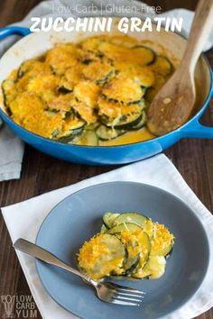 zucchini gratin in a blue casserole dish with a wooden spoon