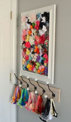 an art piece is hung on the wall with clothes hanging from it's hooks