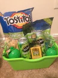 a green basket filled with lots of different types of drinks and condiments on top of a carpeted floor