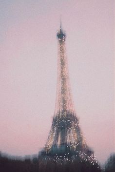 the eiffel tower is lit up with lights in paris, on a foggy day