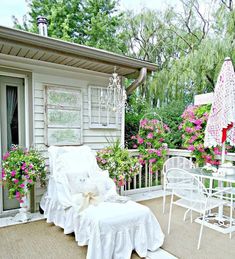 a white chair sitting on top of a patio next to a table and chairs with flowers