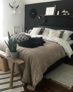 a bedroom with black walls and white bedding has a plant on the end table