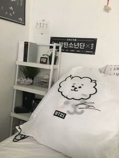 a white bed topped with a pillow covered in a cartoon character on it's side