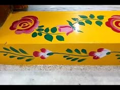 a yellow box with red flowers painted on it