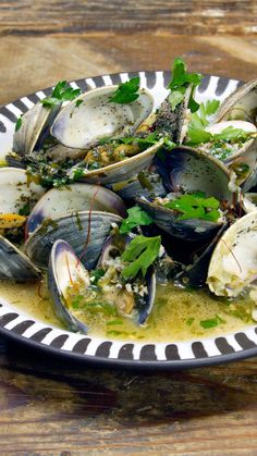 a plate full of clams with parsley on top and sauce in the middle