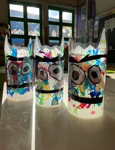 three plastic cups with faces painted on them sitting on top of a white countertop