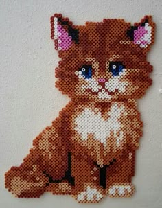 a close up of a cat made out of perler beads on a white wall