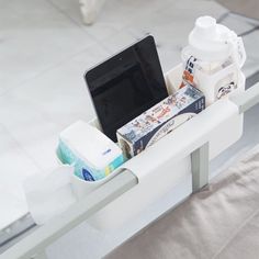 an open laptop computer sitting on top of a white shelf next to a cup and toiletries