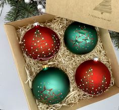 three red and green christmas ornaments in a box