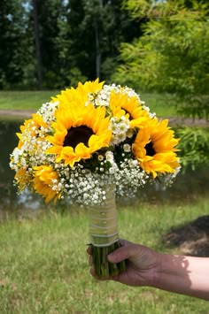 a bouquet of sunflowers and baby's breath is held by a person