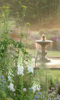 there is a fountain in the middle of some flowers