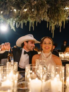 a man and woman sitting at a table with candles