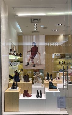 a display case filled with lots of shoes in front of a glass window that has pictures on it