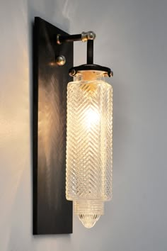 a light that is on the wall next to a glass lamp shade and metal frame