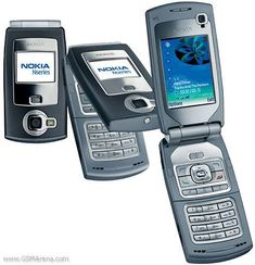 three cell phones are sitting side by side, one has a nokia logo on the screen