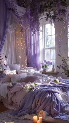 a bed with purple sheets and pillows in a bedroom next to a window filled with candles