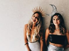 two women standing next to each other in front of a wall with the moon and stars on it