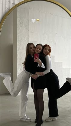 three young women are hugging in front of a mirror with their arms around each other