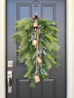 a christmas wreath hanging on the front door with bells and greenery attached to it