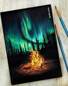 a painting of a campfire with an aurora bore in the background and two colored pencils next to it