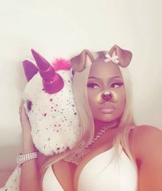 a woman with long blonde hair holding a stuffed unicorn horse toy in her hand and wearing a white bra