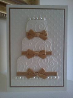 a white card with two tiered cake on the front and brown bows on the back