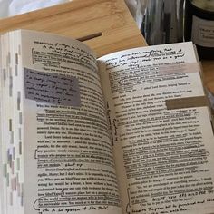 an open book sitting on top of a wooden table next to a bottle of wine