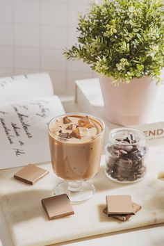 a cup of coffee sitting on top of a table next to some cookies and candy