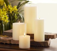 three white candles sitting on top of a wooden table