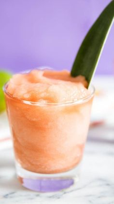 a close up of a drink on a table with a green leaf sticking out of it