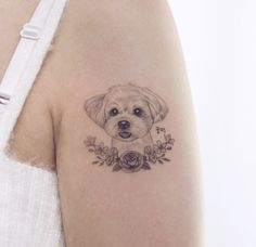 a small dog tattoo on the right arm and shoulder, with flowers around it's neck