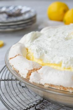 a cake sitting on top of a cooling rack next to lemons and plates in the background