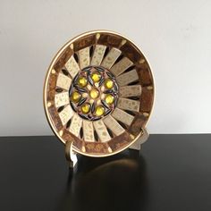 a decorative plate sitting on top of a black table next to a white and yellow wall