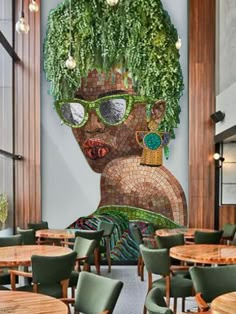 an artistic mural on the wall of a restaurant with green chairs and tables in front of it