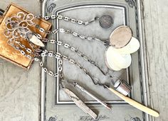 an assortment of silverware and other items on a metal tray with chain around it