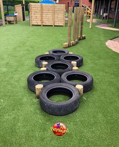 several tires are lined up on the grass in front of a play area at a park