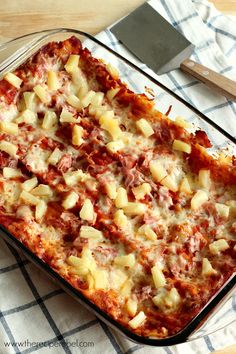 a casserole dish with meat and cheese on it next to a spatula